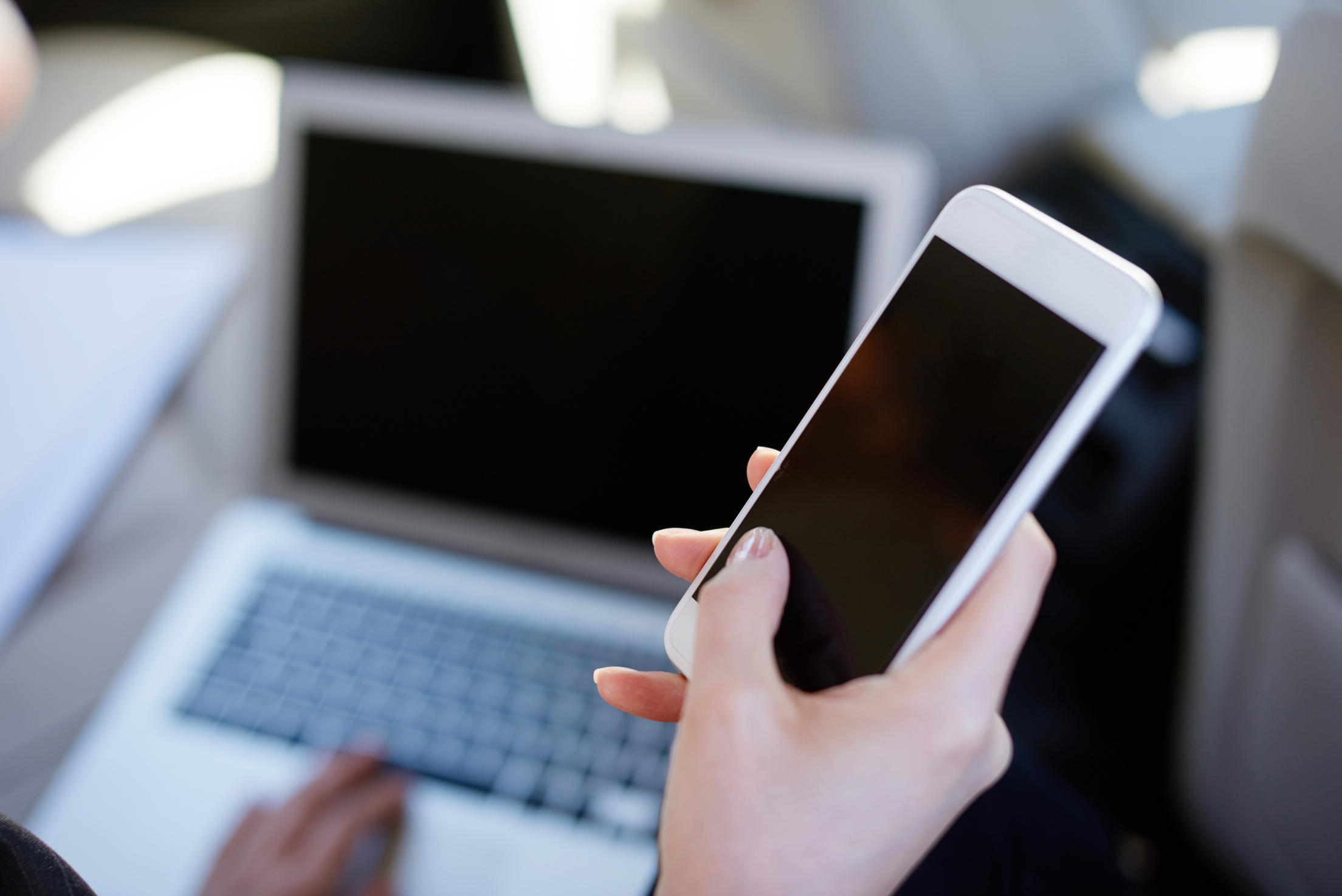 Woman using computer and phone sitting in car